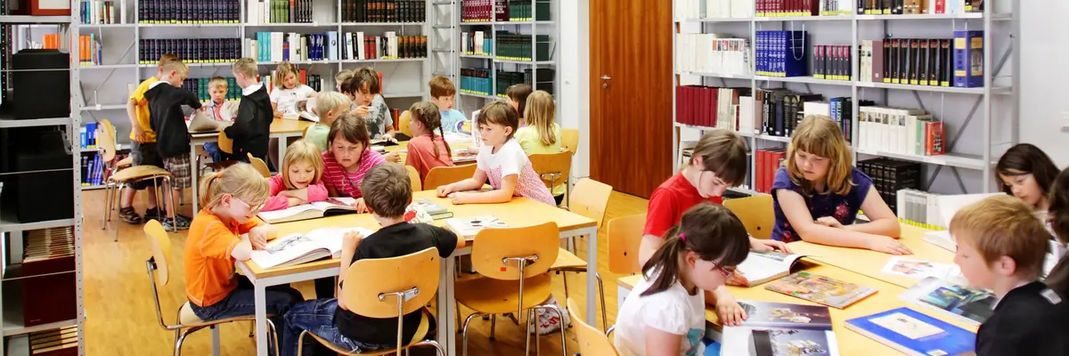 Kinder sitzen und lesen an Tischen im Lesesaal der Kunstbibliothek